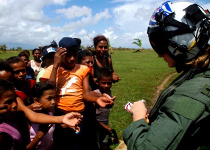 US Navy 070907-N-7540C-031 A U.S. Navy pilot hands out candy to local children while delivering food and water from the multipurpose amphibious assault ship USS Wasp (LHD 1) photo