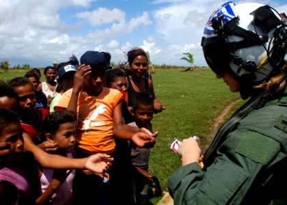 US Navy 070907-N-7540C-031 A U.S. Navy pilot hands out candy to local children while delivering food and water from the multipurpose amphibious assault ship USS Wasp (LHD 1)