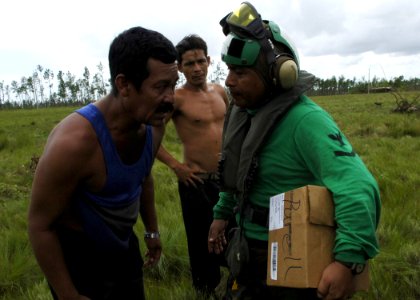 US Navy 070907-N-7540C-048 A Sailor attached to the multi-purpose amphibious assault ship USS WASP (LHD 1), talks with a citizen of Puerto Cabezas as much needed supplies and water are delivered to the area photo