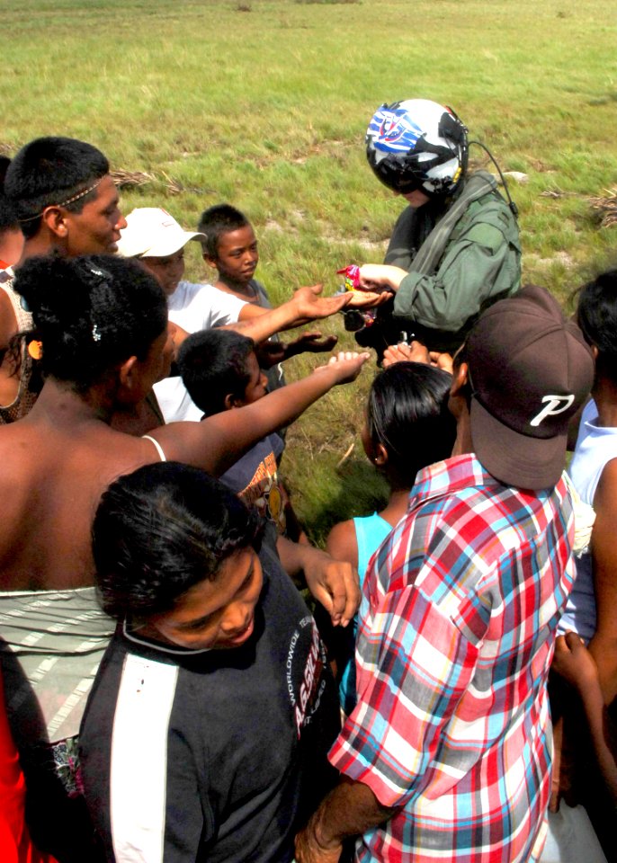 US Navy 070907-N-7540C-028 A U.S. Navy pilot hands out candy to local children while delivering food and water from the multipurpose amphibious assault ship USS Wasp (LHD 1)