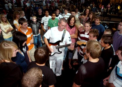 US Navy 070910-N-5208T-005 Musician 2nd Class Robert Collier, of U.S. Navy Band Southwest, the Destroyers, gives guitar lessons to students of West Point Junior High School