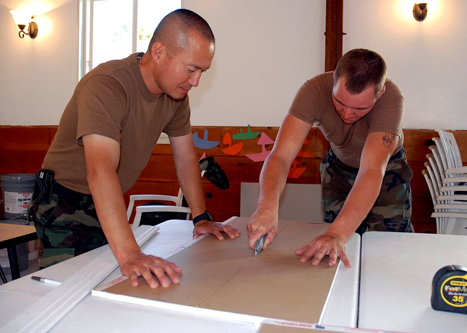 US Navy 070911-N-8547M-044 Lt. Song Hwang, chaplain of Naval Mobile Construction Battalion (NMCB) 5, left, and Builder Constructionman Robert L. Dynda, of the battalion's air detachment, cut sheetrock during a constructio