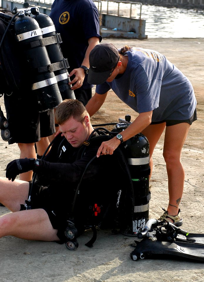 US Navy 070911-F-0827S-003 Chief Explosive Ordnance Disposal Technician Melissa Tackitt helps Lt. Eric Vik into his dive equipment before performing a force protection dive of one of the piers at the Djibouti port