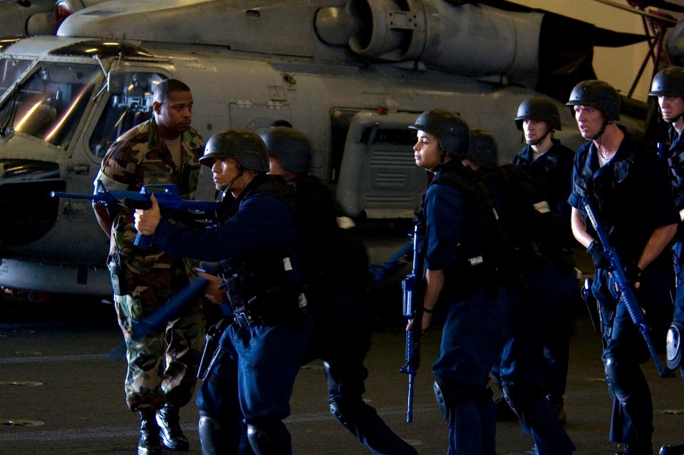 US Navy 070919-N-5387K-008 Anti-terrorism instructor Chief Master-at-Arms Tyjuan Frazier observes shipboard reaction force trainees during a tactical force protection drill in the hangar bay aboard USS Kitty Hawk (CV 63)