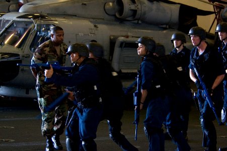 US Navy 070919-N-5387K-008 Anti-terrorism instructor Chief Master-at-Arms Tyjuan Frazier observes shipboard reaction force trainees during a tactical force protection drill in the hangar bay aboard USS Kitty Hawk (CV 63)