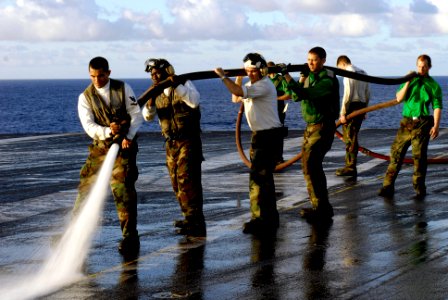 US Navy 070919-N-7883G-030 Sailors assigned to USS Kitty Hawk (CV 63) and Carrier Air Wing (CVW) 5 wash down the flight deck. Wash downs are conducted to remove oily waste from the flight deck and hangar bay