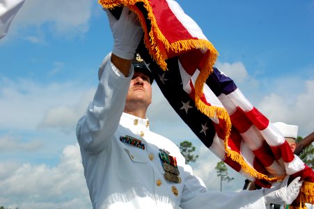 US Navy 070914-N-1057H-340 Command Master Chief Thane A. Halsey, of Naval Mobile Construction Battalion (NMCB) 11, uncases the national ensign during NMCB 11's commissioning ceremony