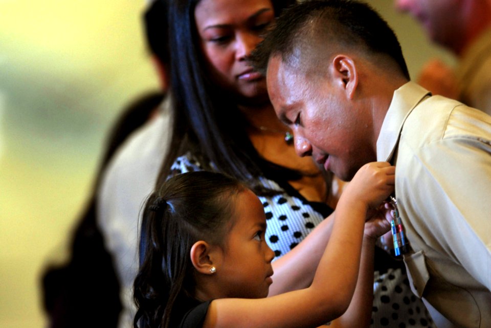 US Navy 070921-N-3659B-088 Chief Personnel Specialist Rodolfo E. Espino has his anchors pinned on by her daughter during a pinning ceremony held in the hangar bay aboard USS Ronald Reagan (CVN 76)