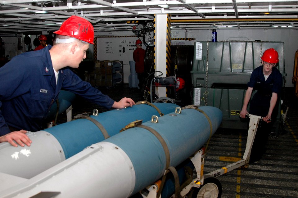 US Navy 070919-N-7128A-046 Aviation Ordnancemen 3rd Class Trevor Curtis, left, and Airman Mathew Linnens move a cart loaded with training bombs during a bomb buildup aboard nuclear-powered aircraft carrier USS Nimitz (CVN 68)