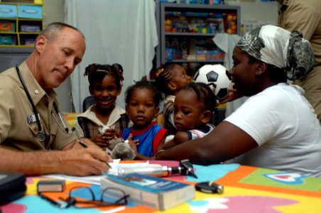 US Navy 070921-N-7088A-125 Cmdr. Craig Martin, attached to Military Sealift Command hospital ship USNS Comfort (T-AH 20), examines a family at the at Moulton Hall Methodist Primary School photo