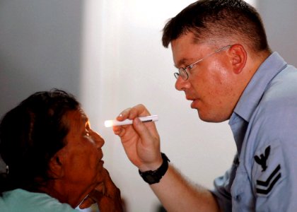 US Navy 070925-N-0194K-183 Hospital Corpsman 2nd Class Mark Andrews, an optician attached to Military Sealift Command hospital ship USNS Comfort (T-AH 20), examines a patient's eyes at Charity Hospital photo