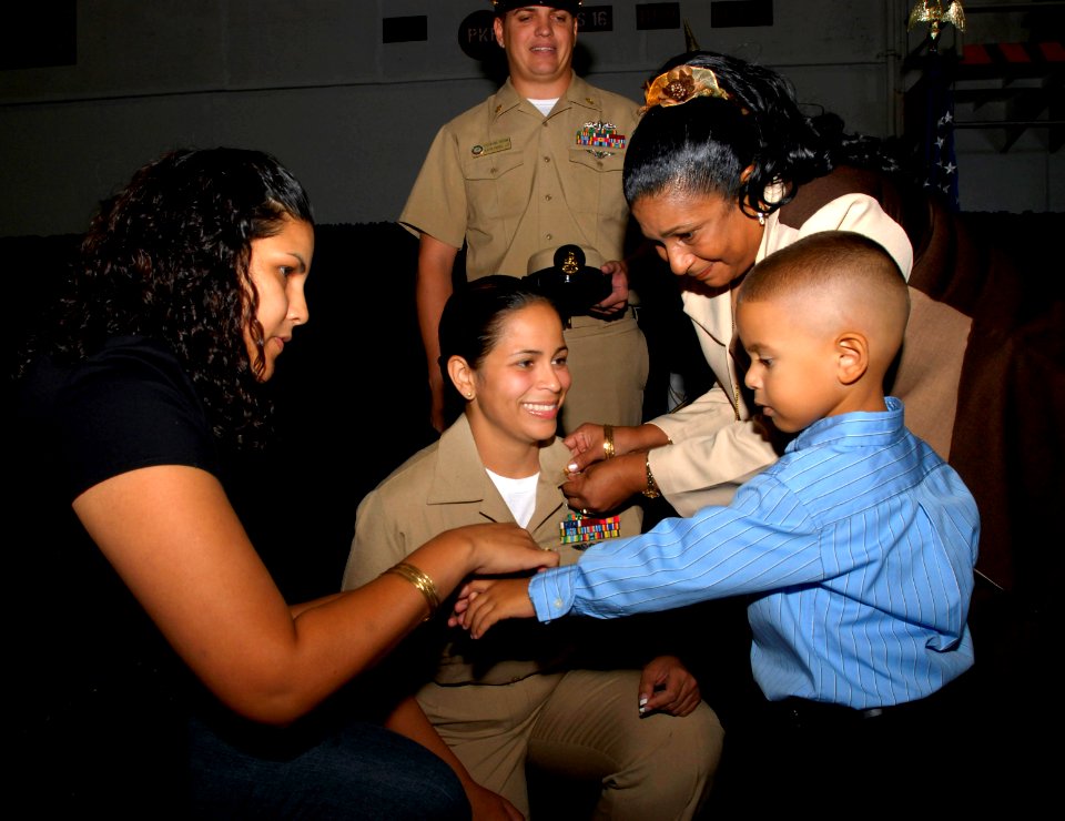 US Navy 070921-N-4133B-051 Family members of Chief Machinist's Mate Orlyn Fernandez pin anchors on her collar during a pinning ceremony held in the hangar bay aboard USS Ronald Reagan (CVN 76)