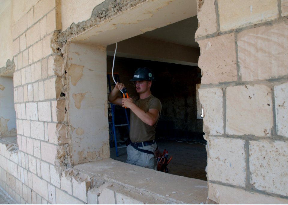 US Navy 070922-N-3560G-005 Utilitiesman Constructionman Steven Shapiro, assigned to Naval Mobile Construction Battalion (NMCB) 4, prepares the electrical wiring for new lights being installed during the conversion of an old Ira