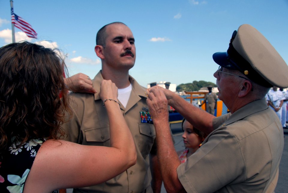 US Navy 070921-N-4399G-277 Chief Electronics Technician William Gaskins has his anchors pinned on by his wife Andrea and his father, a retired chief boatswain's mate, during the chief petty officer pinning ceremony aboard