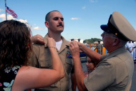 US Navy 070921-N-4399G-277 Chief Electronics Technician William Gaskins has his anchors pinned on by his wife Andrea and his father, a retired chief boatswain's mate, during the chief petty officer pinning ceremony aboard photo