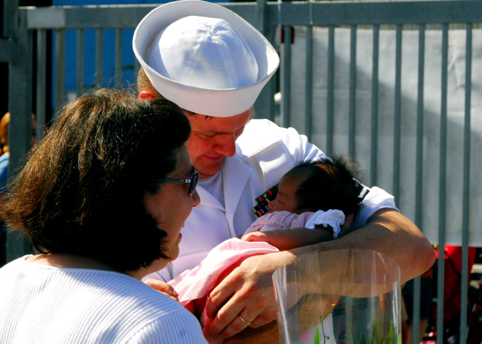 US Navy 070921-N-2638R-005 Machinist's Mate 1st Class Glenn Muller embraces his newborn daughter for the first time on the pier after returning from a deployment aboard USS Kitty Hawk (CV 63)