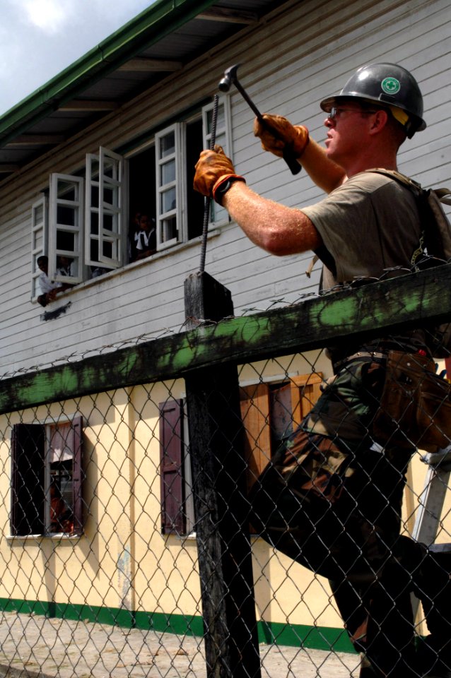 US Navy 070926-N-7088A-116 Builder 1st Class Austin Prewitt, a Seabee with Construction Battalion Maintenance Unit (CBMU) 202 attached to Military Sealift Command hospital ship USNS Comfort (T-AH 20), hammers rebar into a fence