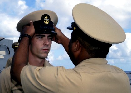 US Navy 070921-N-4649C-078 Chief Fire Controlman Shawn Bell receives his combination cover from Chief Intelligence Specialist Kenyan Thompson during a chief petty officer pinning ceremony aboard Arleigh Burke-class guided-missi