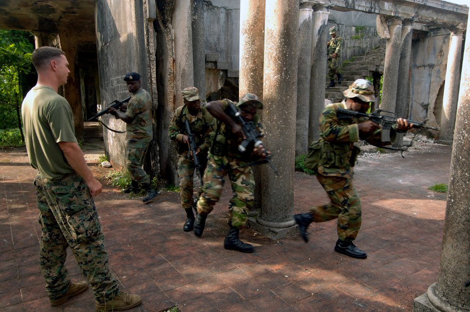 US Navy 070925-N-0989H-405 Sgt. Matthew Heerwald, assigned to a mobile training team, left, observes members of the Jamaica Defense Force practice Close Quarters Battle and room clearing drills during small unit training