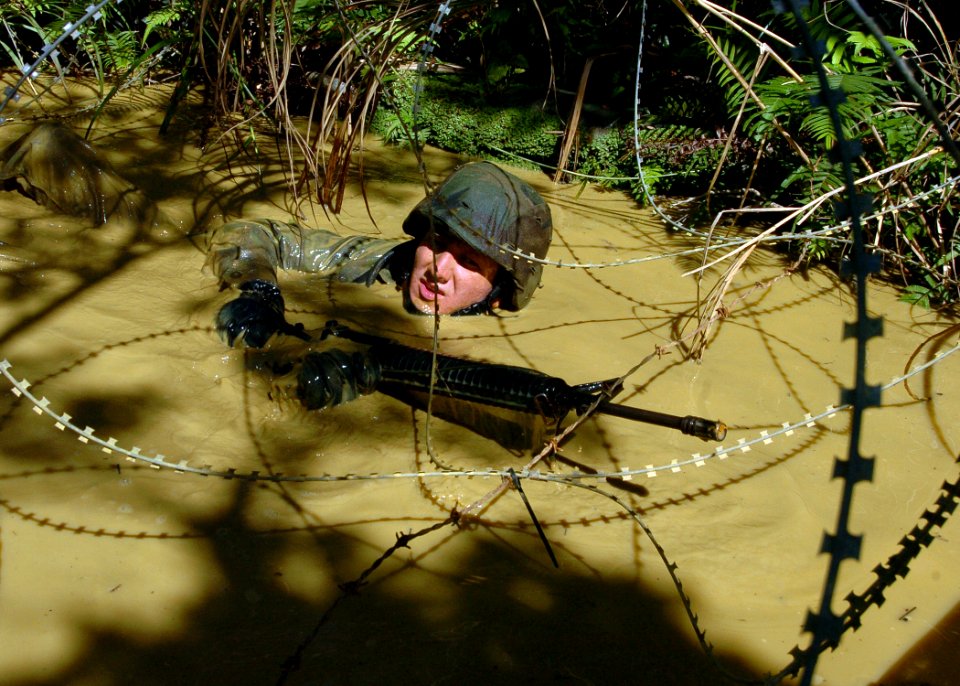 US Navy 070927-N-4267W-130 Steelworker 3rd Class Benjamin Hickok, with Naval Mobile Construction Battalion (NMCB) 7, traverses a mud-filled trench during a jungle warfare training evolution hosted by Marines with the Jungle Wa