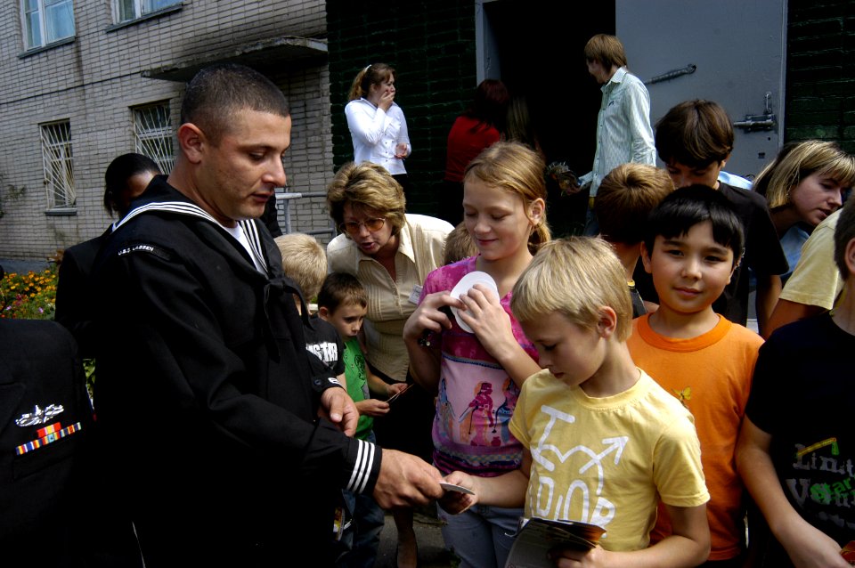 US Navy 070924-N-4649C-002 Gas Turbine System Technician (Mechanical) 1st Class David Ballesteros, of Arleigh Burke-class guided-missile destroyer USS Lassen (DDG 82), hands out toy cars to children at the Mayak Children's Reha