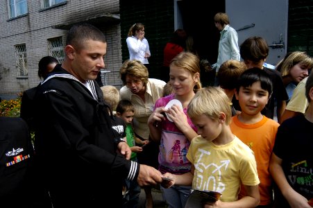 US Navy 070924-N-4649C-002 Gas Turbine System Technician (Mechanical) 1st Class David Ballesteros, of Arleigh Burke-class guided-missile destroyer USS Lassen (DDG 82), hands out toy cars to children at the Mayak Children's Reha