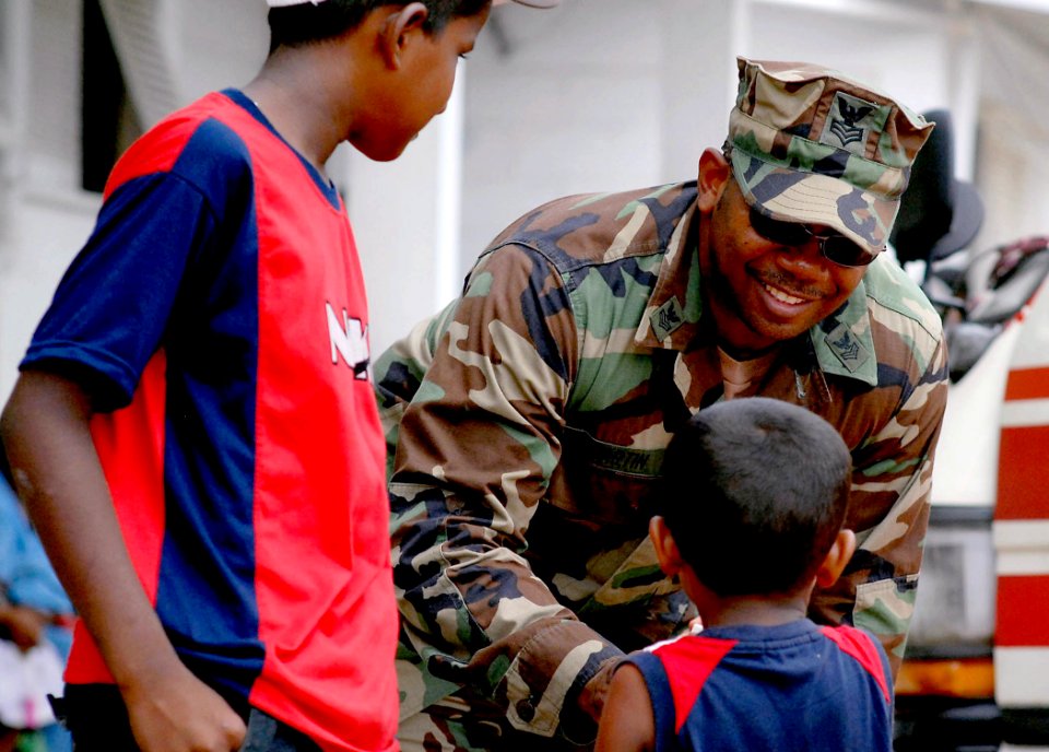 US Navy 070925-N-0194K-119 Master-at-Arms 1st Class Darryl Martin, attached to Military Sealift Command hospital ship USNS Comfort (T-AH 20), shakes hands with a young boy at Charity Hospital