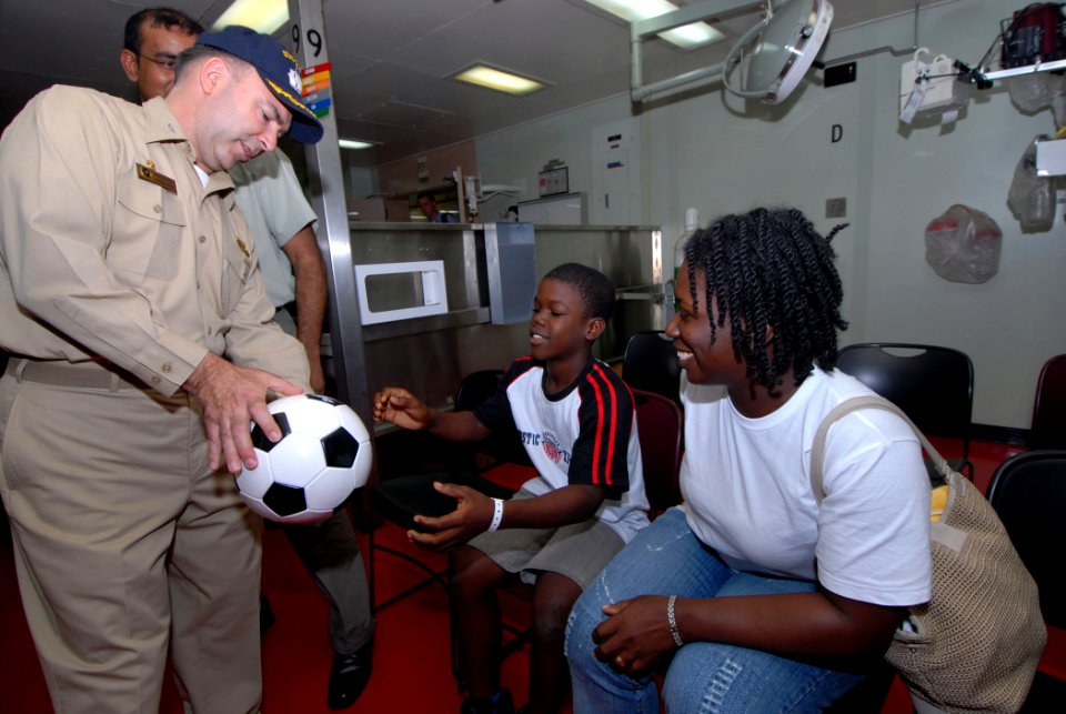US Navy 070929-N-8704K-025 Capt. Bob Kapcio, mission commander for Military Sealift Command hospital ship USNS Comfort (T-AH 20), gives a soccer ball to a young boy as his mother looks