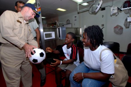 US Navy 070929-N-8704K-025 Capt. Bob Kapcio, mission commander for Military Sealift Command hospital ship USNS Comfort (T-AH 20), gives a soccer ball to a young boy as his mother looks photo