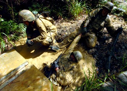 US Navy 070927-N-4267W-162 Seabees with Naval Mobile Construction Battalion (NMCB) 7 work together to exit a mud-filled trench during a jungle warfare training evolution hosted by Marines with the Jungle Warfare Training Comman