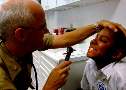 US Navy 070926-N-6278K-073 Cmdr. Arne Anderson, a pediatrician attached to Military Sealift Command hospital ship USNS Comfort (T-AH 20), examines a patient's teeth at the Project Dawn at Liliendaal care site photo
