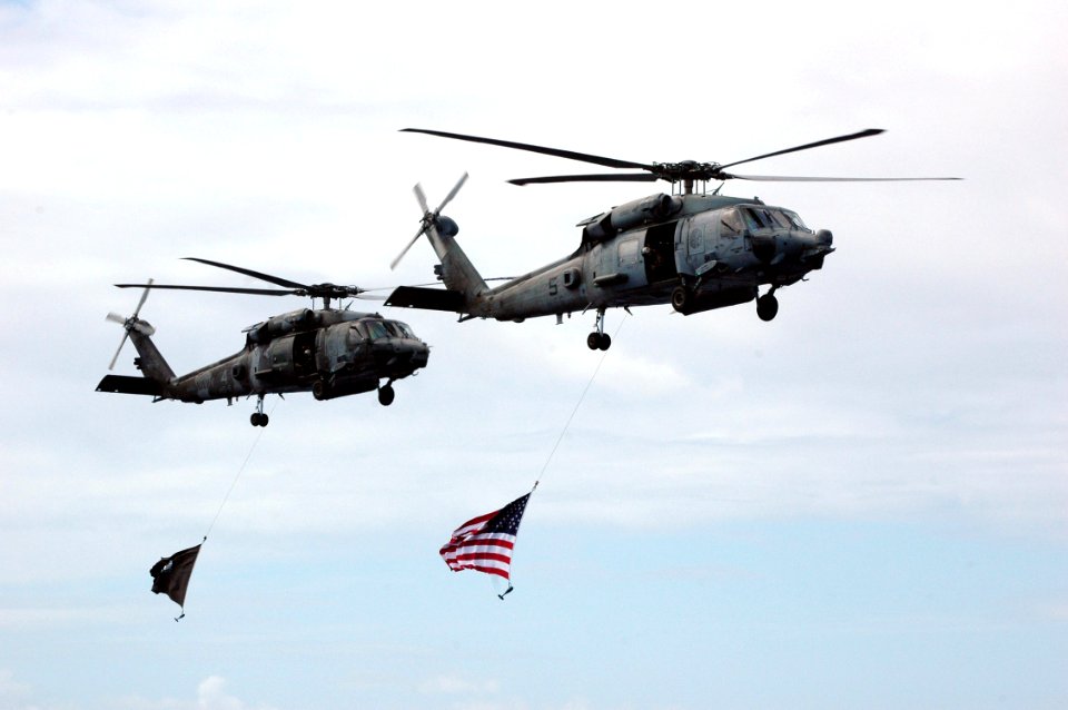 US Navy 070926-N-7128A-060 Two SH-60F Seahawks, assigned to the Indians of Helicopter Anti-Submarine Squadron (HS) 6, fly the American and POW-MIA flags above the flight deck of the nuclear-powered aircraft carrier USS Nimitz (