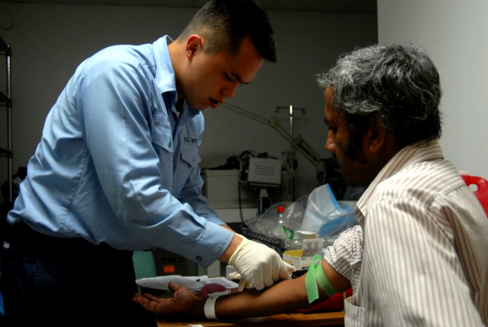 US Navy 070930-N-8704K-041 Hospital Corpsman 3rd Class Ishmael Finn, attached to Military Sealift Command hospital ship USNS Comfort (T-AH 20), draws blood from a patient