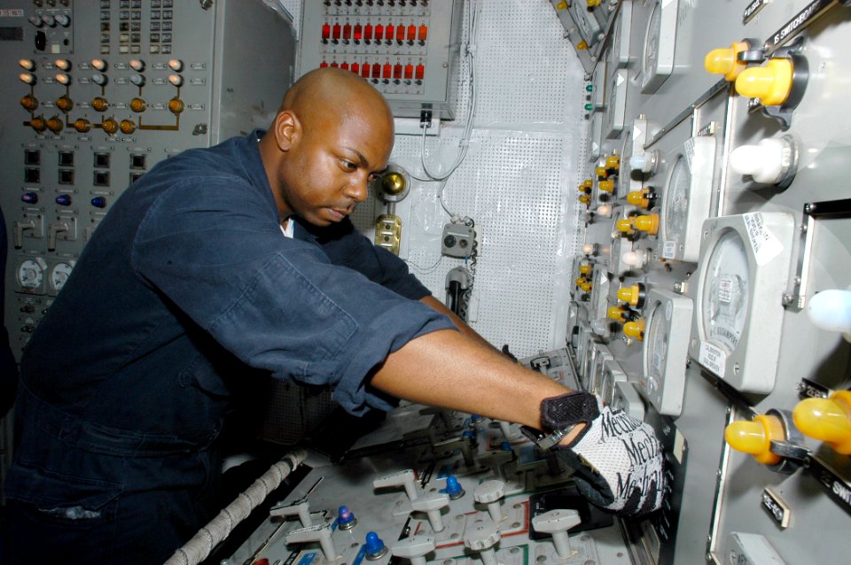 US Navy 070929-N-5642P-128 Engineman 2nd Class Chuck Levy operates a switchboard in the aft pit booth aboard amphibious assault ship USS Kearsarge (LHD 3)