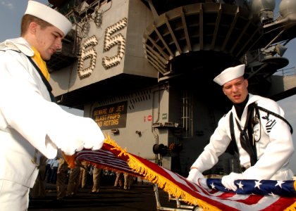 US Navy 071001-N-5928K-005 Gunner's Mate 1st Class Kirt Bunn, right, and Damage Controlman 2nd Class Brian Schneider fold the national ensign after a change of command ceremony