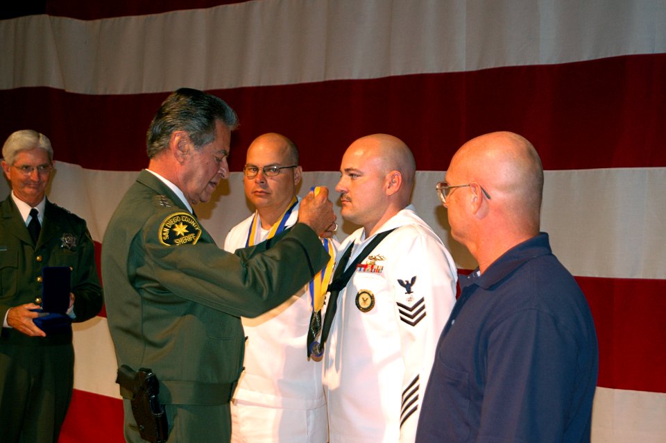 US Navy 071002-N-6999H-004 Mineman 1st Class Ralph Bishop, left, and Electronics Technician 1st Class Verlon Cox attached to USS Freedom (LCS 1) and Clarence Good, receive the Distinguished Service Award