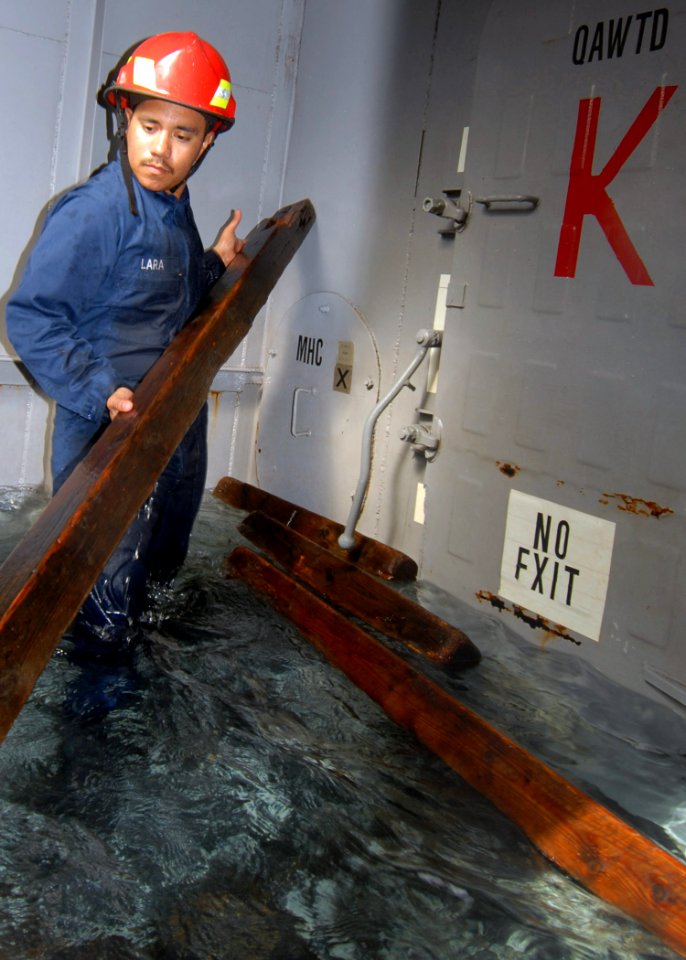 US Navy 071004-N-8544C-004 Hull Technician Fireman Robert Lara, attached to Precommissioning Unit (PCU) George H. W. Bush (CVN 77), selects a prefabricated piece of wood for shoring while training in the mobile damage control t