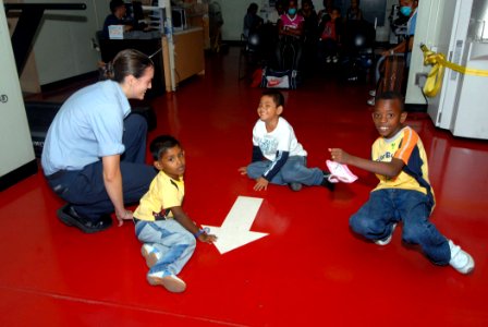 US Navy 071004-N-8704K-039 Mass Communication Specialist 3rd Class Kelly Barnes entertains children awaiting treatment on board Military Sealift Command hospital ship USNS Comfort (T-AH 20), anchored off the coast of Paramaribo