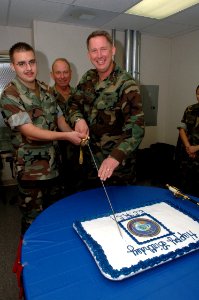 US Navy 071010-N-2456S-081 Information Systems Technician Seaman Bradley Encinas and Capt. Jeff McKenzie, commanding officer of Expeditionary Combat Readiness Command (ECRC), cut the cake as the youngest and oldest members of E
