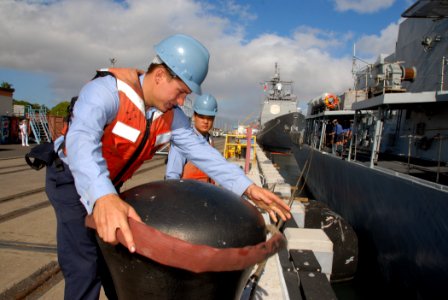 US Navy 071025-N-4965F-007 Seaman Sam McWhorter, assigned to guided-missile cruiser USS Chosin (CG 65), performs line handling duties for British Royal Navy frigate HMS Monmouth (F235) as she moors pierside Naval Station Pearl
