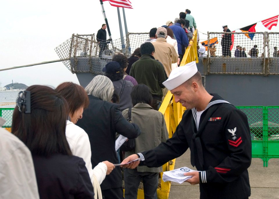 US Navy 071027-N-9520G-005 Electronics Technician 2nd Class Adam Haupt hands out welcome aboard pamphlets as hundreds of visitors from the Hokkaido area line up for a chance to tour guided-missile destroyer USS Fitzgerald (DDG