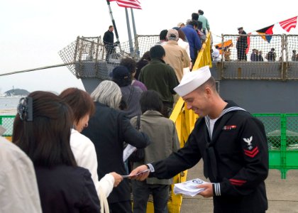 US Navy 071027-N-9520G-005 Electronics Technician 2nd Class Adam Haupt hands out welcome aboard pamphlets as hundreds of visitors from the Hokkaido area line up for a chance to tour guided-missile destroyer USS Fitzgerald (DDG photo