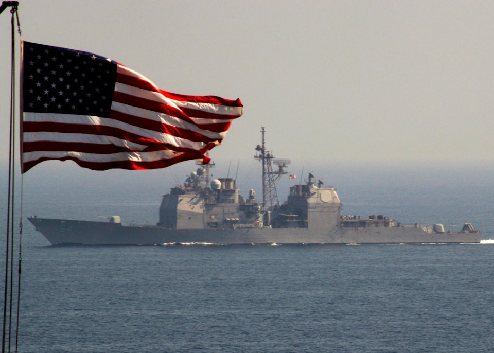 US Navy 071029-N-5928K-008 The flag overshadows guided-missile cruiser USS Gettysburg (CG 64) as she steams alongside nuclear-powered aircraft carrier USS Enterprise (CVN 65)