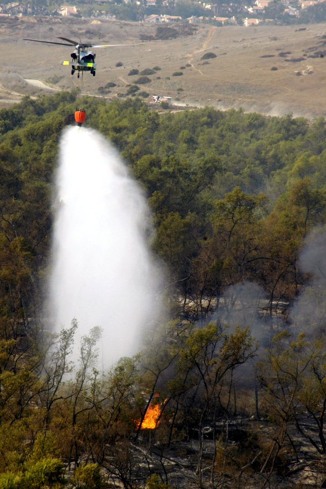 US Navy 071024-N-6597H-232 An MH-60S Seahawk helicopter assigned to Helicopter Sea Combat Squadron (HSC) 85, dumps 420 gallons of water below them on wildfires burning in San Diego County