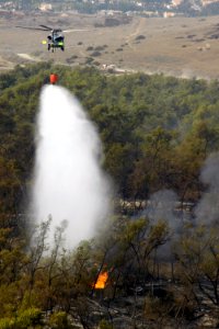 US Navy 071024-N-6597H-232 An MH-60S Seahawk helicopter assigned to Helicopter Sea Combat Squadron (HSC) 85, dumps 420 gallons of water below them on wildfires burning in San Diego County