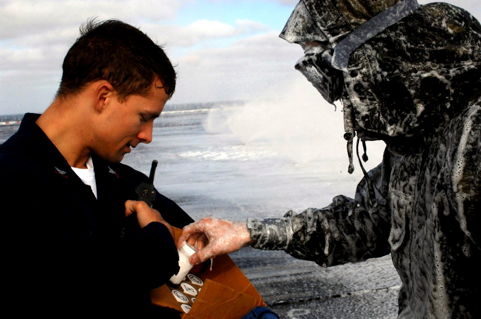 US Navy 071030-N-4133B-064 Damage Controlman Fireman Ryan Anderson hands a sample of aqueous film forming foam (AFFF) to Damage Controlman 2nd Class William Koziol aboard Nimitz-class aircraft carrier USS Ronald Reagan (CVN 76)