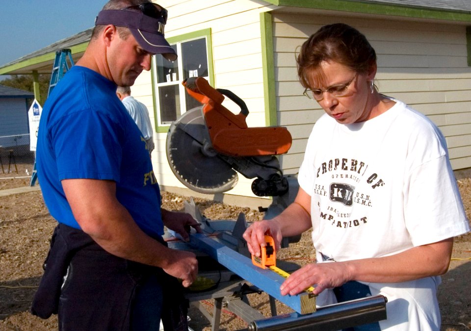 US Navy 071031-N-3750S-043 Lt. Cmdr. Bradley Slocum, and Chief Yeoman Nora Lundberg, attached to the Navy Operational Support Center San Antonio, cut pieces of wood for the porch of a Habitat for Humanity project house