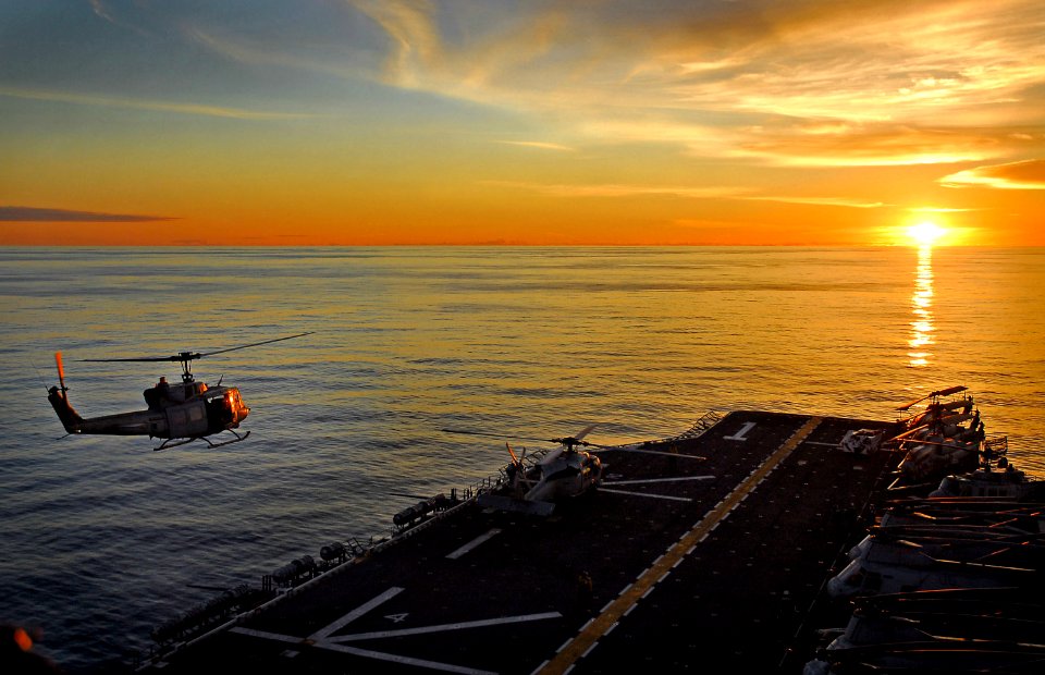 US Navy 071108-N-4774B-046 A UH-1N Huey takes off from the flight deck of amphibious assault ship USS Tarawa (LHA 1) during sunset over the Pacific Ocean