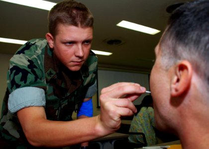 US Navy 071109-N-1120L-002 Hospital Corpsman 2nd Class Thomas Robertson, assigned to Naval Mobile Construction Battalion (NMCB) 7, takes a mouth swab from a Seabee during the Bone Marrow Registry Drive