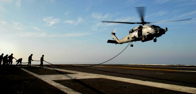 US Navy 071103-N-7981E-407 Members of Helicopter Visit, Board, Search, and Seizure (HVBSS) Team 1, maintain control of their line after fast-roping from an SH-60F Seahawk onto the flight deck of Nimitz-class aircraft carrier US